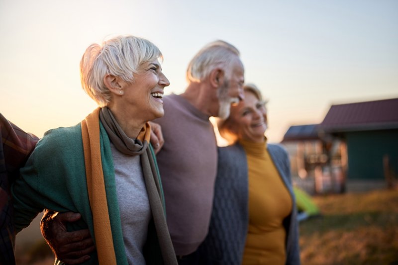 Group of happy mature friends enjoying while walking in autumn day in nature.