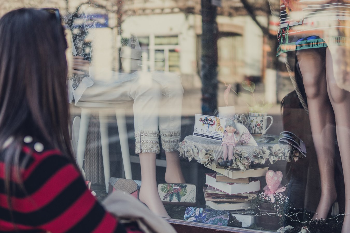 Eine Frau betrachtet ein Schaufenster mit Geschenkartikeln und Kleidern.