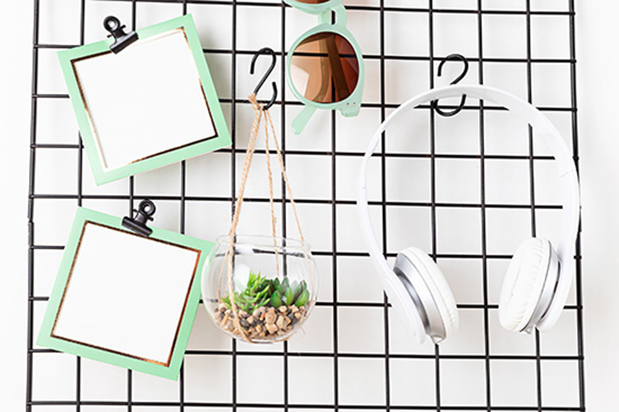 La photo montre une grille métallique usagée transformée en système de rangement destiné à suspendre des objets personnels comme un casque audio, des lunettes de soleil ou un bloc-notes: des idées DIY pour matériaux d’upcycling.