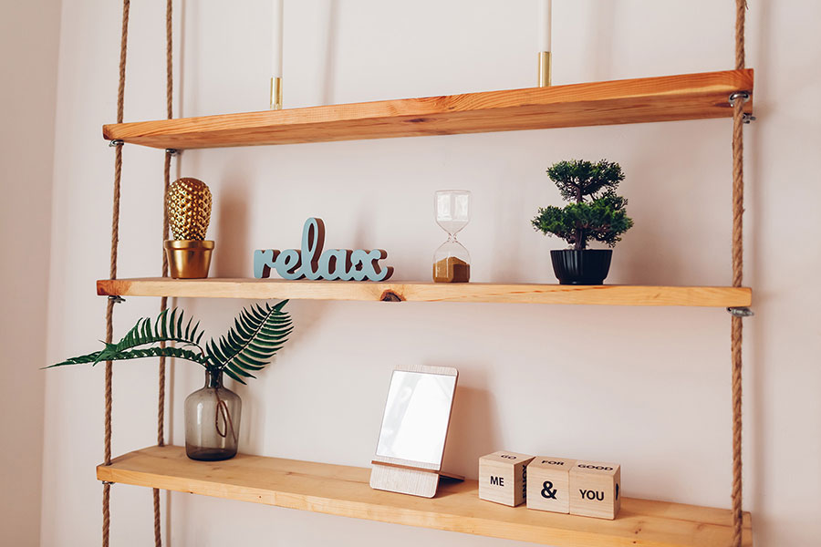 La photo montre une étagère suspendue en bois, fixée au plafond par des cordes. Elle se compose de trois planches de bois brut: des idées DIY pour matériaux d’upcycling.