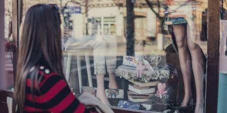 Eine Frau betrachtet ein Schaufenster mit Geschenkartikeln und Kleidern.