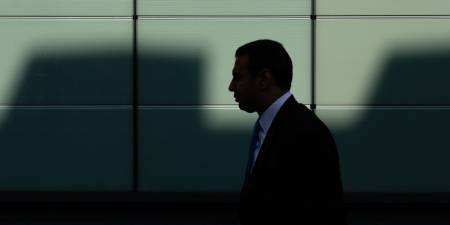 Silhouette of a banker walking in the shadows.
