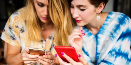 Deux femmes sont absorbées par leurs téléphones mobiles.